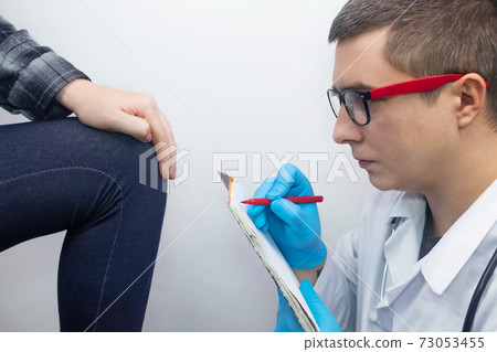 A woman suffers from knee pain. Examination by an orthopedist and traumatologist. Redness and swelling of the legs, torn meniscus or knee bursitis. The doctor examines 73053455