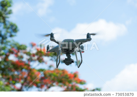 White drone with camera flying in summer 73053870