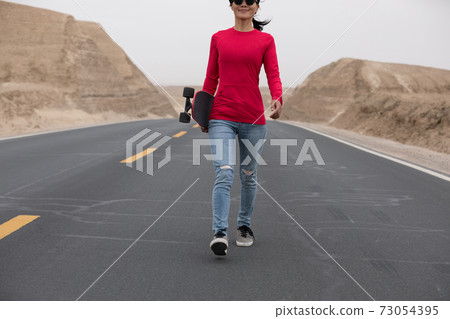 Asian woman skateboarder skateboarding in the wide world Asian woman skateboarder skateboarding in the wide world 73054395