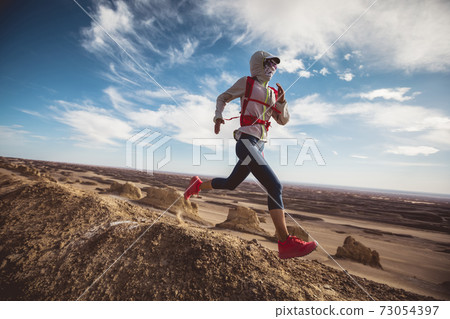 Woman trail runner cross country running  on sand desert dunes 73054397