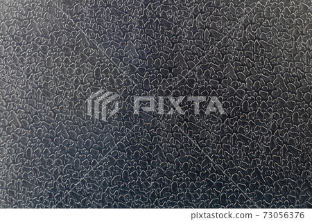 Macro photo of black artificial leather with a special print in the form of scales or irregular islets. 73056376