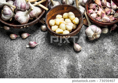 Peeled slices of fresh garlic in bowls. Peeled slices of fresh garlic in bowls. 73056407