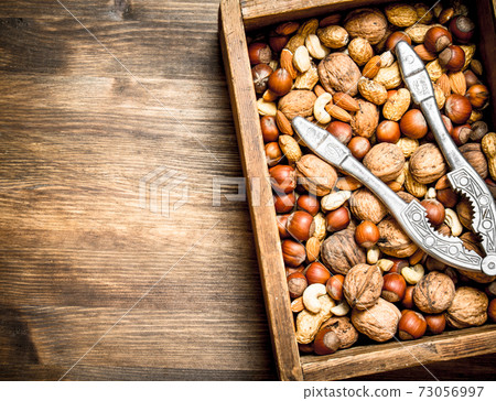 Different nuts with the Nutcracker in the old box. Different nuts with the Nutcracker in the old box. 73056997