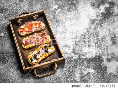 Sandwiches with meat, salami, seafood and fresh vegetables. Sandwiches with meat, salami, seafood and fresh vegetables. 73057115