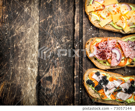 Sandwiches with seafood, salami, cheese and vegetables. 73057144