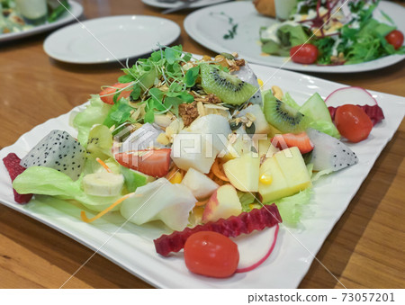 Fresh mix vegetables and fruits salad on wooden table. 73057201