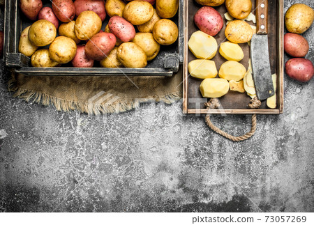 Peeled potatoes on a wooden board. 73057269