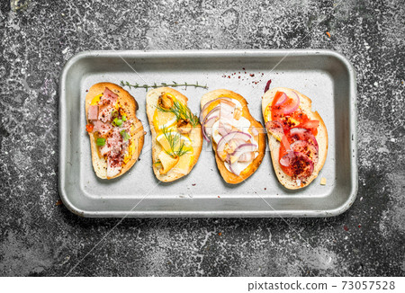 Various sandwiches with red caviar, bacon, cheese and fresh vegetables on a steel tray. Various sandwiches with red caviar, bacon, cheese and fresh vegetables on a steel tray. 73057528