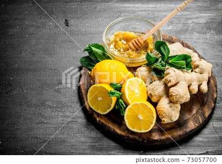 Fresh ginger with honey and lemons on the Board. 73057700