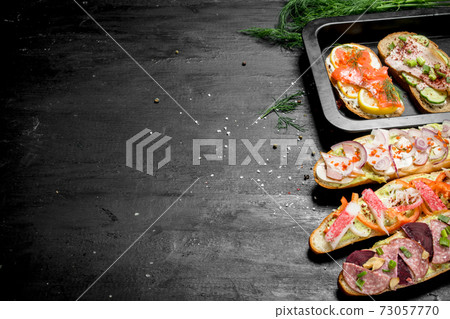 Sandwiches with bacon, salami, crab meat and vegetables. Sandwiches with bacon, salami, crab meat and vegetables. 73057770