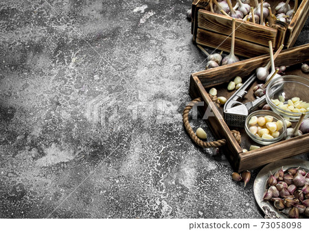 Fresh garlic with a press tool on a wooden tray. Fresh garlic with a press tool on a wooden tray. 73058098