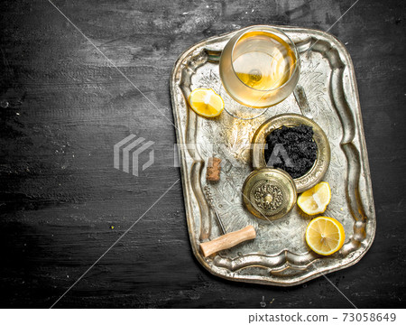 Black caviar with white wine on the old tray. 73058649
