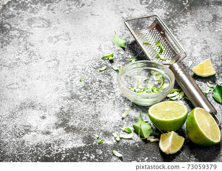Fresh limes with grater and zest in a bowl. Fresh limes with grater and zest in a bowl. 73059379