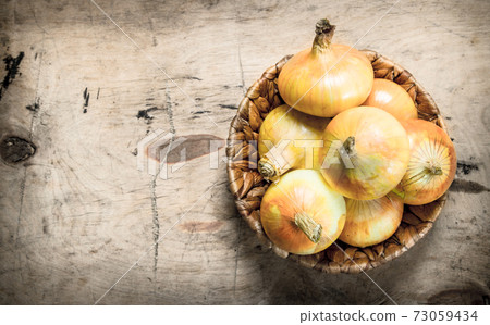 Fresh onions in a basket. On wooden background. Fresh onions in a basket. On wooden background. 73059434