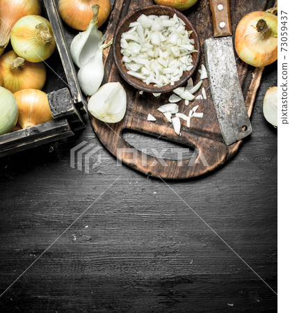 Sliced onion on a cutting board with an old hatchet. Sliced onion on a cutting board with an old hatchet. 73059437