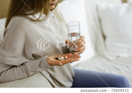 Close-up woman holding pills time to take medications, cure for headache, high blood pressure pain killer drugs at home. Stay at home concept during Coronavirus pandemic Close-up woman holding pills time to take medications, cure for headache, high blood pressure pain killer drugs at home. Stay at home concept during Coronavirus pandemic 73059531