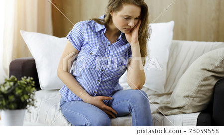 Tired upset woman worried about tiredness from domestic work and self isolation quarantine for COVID-19 Coronavirus 73059558