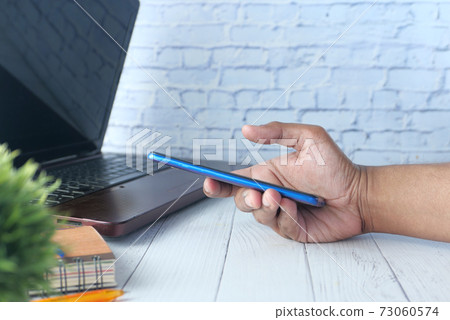 side view of young man hand using smart phone. on table side view of young man hand using smart phone. on table 73060574