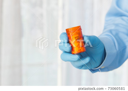 doctor hand in protective glass holding pill container  73060581
