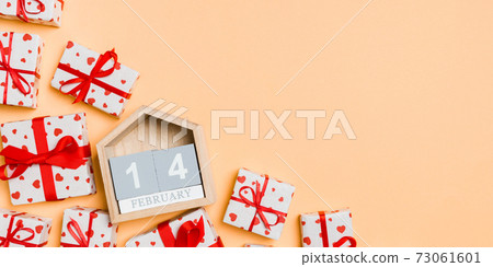 Top view of gift boxes with red hearts and wooden calendar on colorful background. The fourteenth of february. St Valentine's day concept with copy space Top view of gift boxes with red hearts and wooden calendar on colorful background. The fourteenth of february. St Valentine's day concept with copy space 73061601