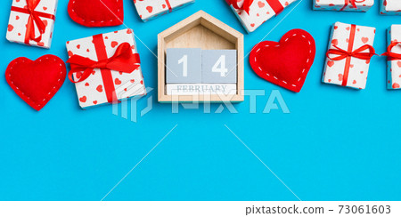 Top view of gift boxes, wooden calendar and red textile hearts on colorful background. The fourteenth of february. St Valentine's day concept with copy space Top view of gift boxes, wooden calendar and red textile hearts on colorful background. The fourteenth of february. St Valentine's day concept with copy space 73061603
