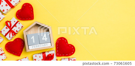 Holiday composition of gift boxes, wooden calendar and red textile hearts on colorful background with empty space for your design. The fourteenth of February. Top view of Valentine's Day concept 73061605