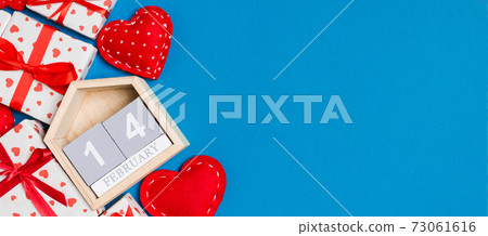 Top view of gift boxes, wooden calendar and red textile hearts on colorful background. The fourteenth of february. St Valentine's day concept with copy space Top view of gift boxes, wooden calendar and red textile hearts on colorful background. The fourteenth of february. St Valentine's day concept with copy space 73061616