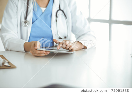 Unknown woman-doctor standing in clinic and using tablet pc, close-up. Data and best service in medicine and healthcare 73061888