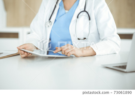 Unknown woman-doctor standing in clinic and using tablet pc, close-up. Data and best service in medicine and healthcare 73061890