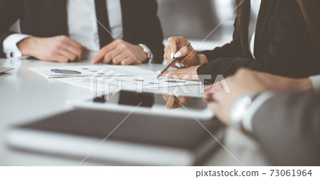 Unknown businessmen and woman sitting, working and discussing questions at meeting in modern office, close-up 73061964