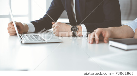 Unknown business people using laptop computer at the desk in modern office. Businessman or male entrepreneur is working with his colleague. Teamwork and partnership concept 73061965