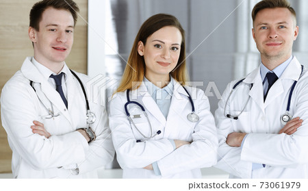 Group of modern doctors standing as a team with arms crossed in hospital office. Physicians ready to examine and help patients. Medical help, insurance in health care, best treatment and medicine Group of modern doctors standing as a team with arms crossed in hospital office. Physicians ready to examine and help patients. Medical help, insurance in health care, best treatment and medicine 73061979