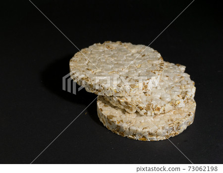 Grain crispbreads crispy rice and diet bread. Stack of puffed whole grain crispbread. Rice cake puffed rice on black background Grain crispbreads crispy rice and diet bread. Stack of puffed whole grain crispbread. Rice cake puffed rice on black background 73062198