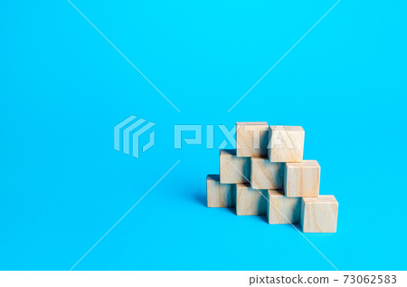 Wooden blocks pyramid on a blue background. Slide for presentation. Copy space, place for text. Steps. Minimalism. Simple shapes geometry. Wooden blocks pyramid on a blue background. Slide for presentation. Copy space, place for text. Steps. Minimalism. Simple shapes geometry. 73062583