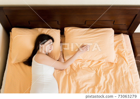 beautiful young pregnant woman lying in bed, top view. the girl suffers from the fact that her husband left her beautiful young pregnant woman lying in bed, top view. the girl suffers from the fact that her husband left her 73063279