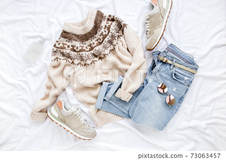 Female fashion look with stylish clothes and accessories. Women's warm sweater, jeans, sneakers. Modern and casual outfit. Flat lay, top view. 73063457