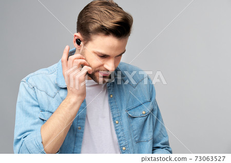 Close up portrait of cheerful young man enjoying listening to music wearing casual jeans outfit Close up portrait of cheerful young man enjoying listening to music wearing casual jeans outfit 73063527