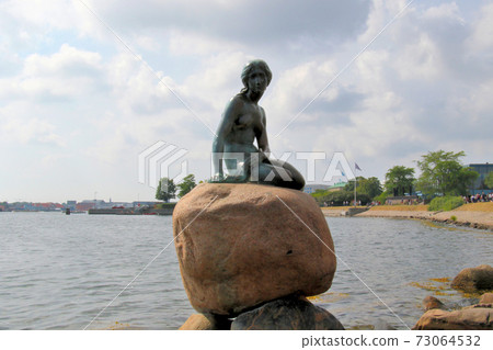 A tourist attraction in Copenhagen, Denmark, a mermaid princess sitting on a large stone, the background is the Castelled side A tourist attraction in Copenhagen, Denmark, a mermaid princess sitting on a large stone, the background is the Castelled side 73064532