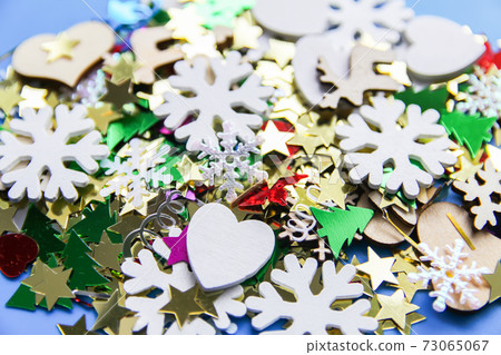 Christmas and New Year decorative background with small wooden snowflakes. Colorful tinsel. Festive confetti. Christmas and New Year decorative background with small wooden snowflakes. Colorful tinsel. Festive confetti. 73065067