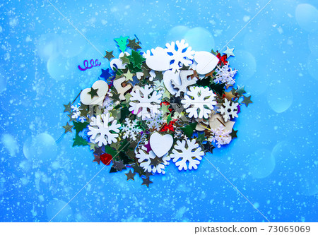 Christmas and New Year decorative background with small wooden snowflakes. Colorful tinsel. Festive confetti. Christmas and New Year decorative background with small wooden snowflakes. Colorful tinsel. Festive confetti. 73065069