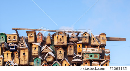 Many different forms of bird feeders.Birdhouses hang on a wooden fence 73065185