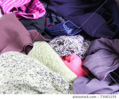 Home wardrobe with different clothes. Small space organization. The contrast of order and disorder. Home wardrobe with different clothes. Small space organization. The contrast of order and disorder. 73065259