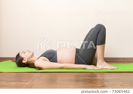 beautiful young pregnant woman sitting on mat in yoga pose at the home. Pregnancy Yoga and Fitness concept at coronavirus time beautiful young pregnant woman sitting on mat in yoga pose at the home. Pregnancy Yoga and Fitness concept at coronavirus time 73065462