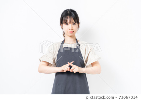 Young woman in an apron making NG gestures Young woman in an apron making NG gestures 73067014