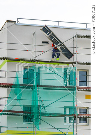 demolition of scaffolding after thermal insulation and painting of the facade of an apartment house demolition of scaffolding after thermal insulation and painting of the facade of an apartment house 73067122