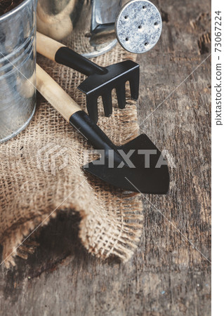 Garden tool, shovel, rake, watering can, bucket, bag on a wooden old brown background, close-up Garden tool, shovel, rake, watering can, bucket, bag on a wooden old brown background, close-up 73067224