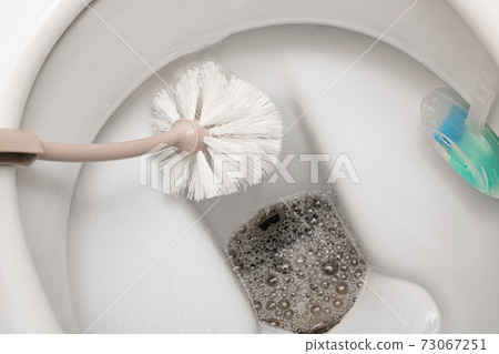 Brush cleans a white toilet close up Brush cleans a white toilet close up 73067251