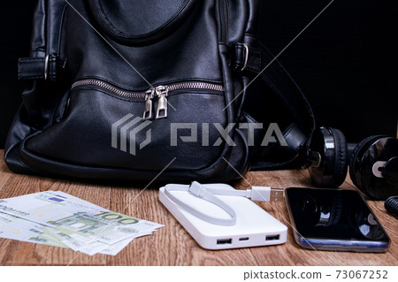 Mobile phone, power bank, bag, money and headphones on wooden table Mobile phone, power bank, bag, money and headphones on wooden table 73067252