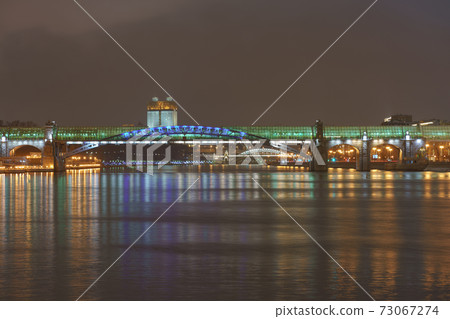 Moscow bright illuminated cityscape. Andreevsky (Pushkinsky) pedestrian bridge, Moskva river, Gorky park, Academy of sciences. Neskuchny Garden. dark winter night sky during coronavirus pandemic time 73067274