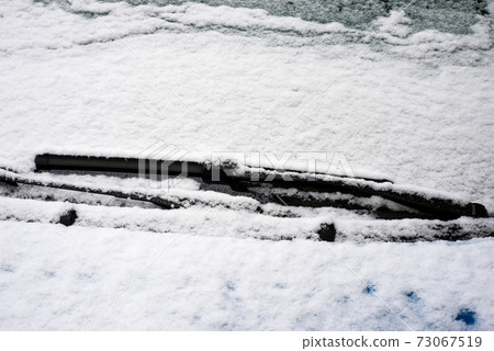 Closeup of windscreen of car parked in the street covered by the snow Closeup of windscreen of car parked in the street covered by the snow 73067519